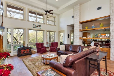 Bright living room with high ceilings, comfortable seating, and views of the porch and ranch area. Designed for guests to feel welcomed and at home, after an adventurous day on the lake or at the golf course!
