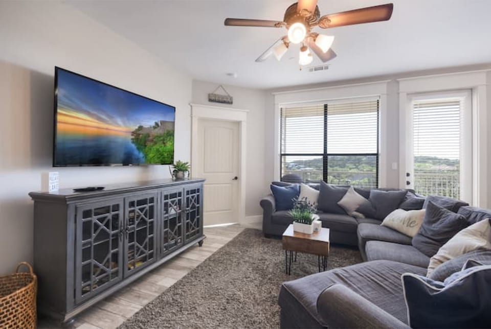 Bright living room with comfortable seating, smart TV, and large windows overlooking the Hill Country near Lake Travis