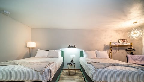 Inviting double queen room with soft lighting, modern bedding, stylish decor, and a comfortable layout for families or groups.