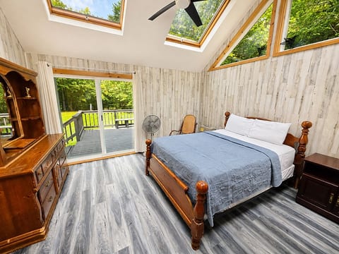 Bright and inviting bedroom featuring beautiful natural light, vaulted ceilings, and direct access to the outdoor deck.