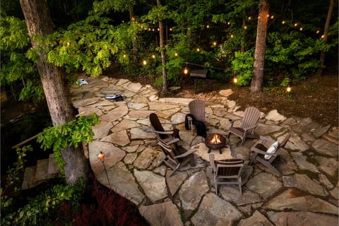 Private wooded patio with fire pit, Adirondack seating, and string lights