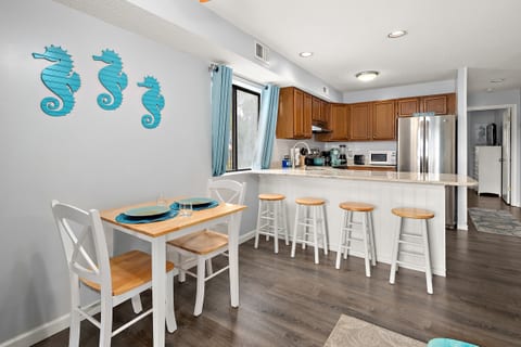 Dining area with table for two plus four barstools at kitchen counter.