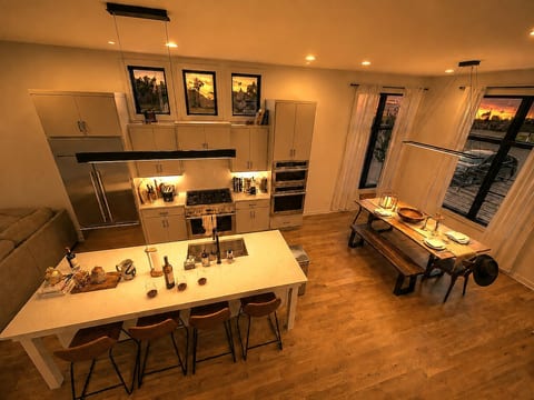 Kitchen island at golden hour — bar seating for 4, pendant lighting, original wall art — pour something and stay a while