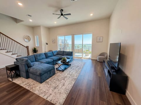 Bright waterfront living room with large sectional and balcony views