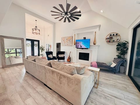 Bringh open-concept living room w/soaring vaulted ceilings, plush seating, fireplace w/TV, oversized statement windmill fan-great area to gather.
