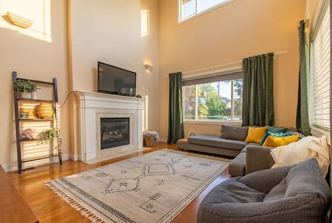 Sunny living room with high ceilings, fireplace, and cozy seating