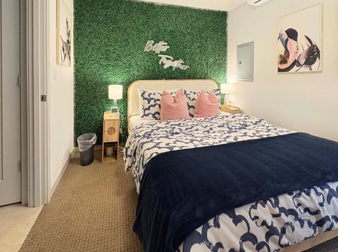 Stylish bedroom with green accent wall, cozy queen bed + warm lighting