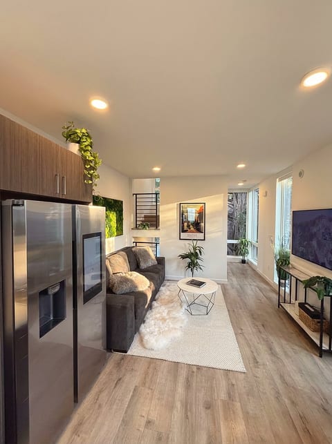 Bright modern living area with sleek kitchen, big TV, and cozy sofa lounge.
