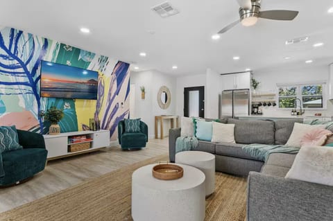 Relax in the living room with a smart TV, ceiling fan, and comfy seating.