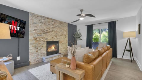 Living room with a stone fireplace and leather sectional, made for movie nights once the air turns cool.