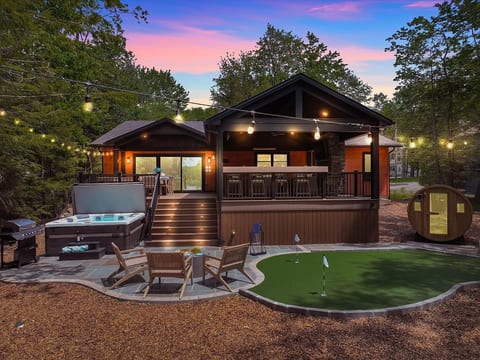 Outdoor paradise with hot tub, sauna, mini golf, grill station, and elevated deck for unforgettable stays.