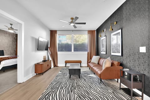 Spacious main living room with Smart TV, Remote Controlled Ceiling Fan and a futon couch.