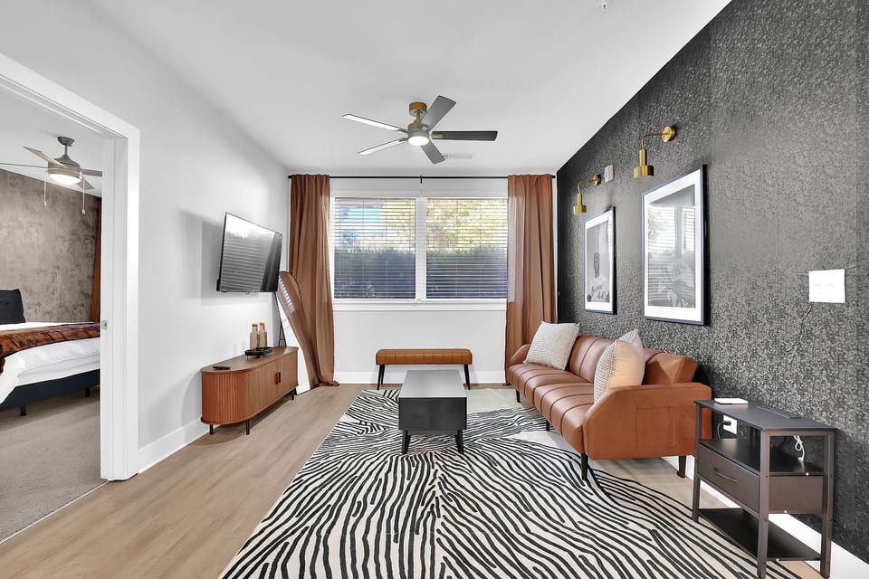 Spacious main living room with Smart TV, Remote Controlled Ceiling Fan and a futon couch.