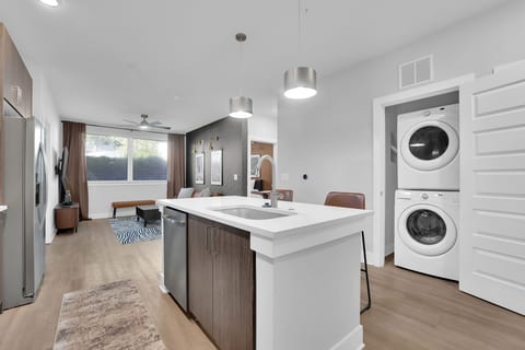 Fully equipped modern kitchen with quartz countertops, washer/dryer, and open living space.