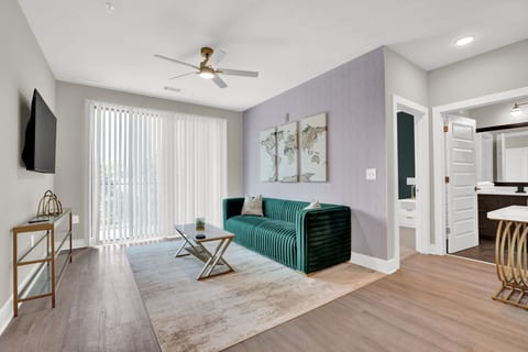 Bright and stylish living room with Smart TV, comfortable seating, and private balcony access.