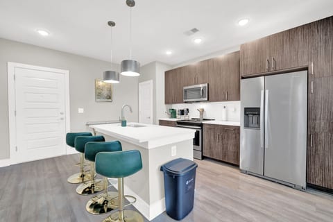 Modern kitchen with quartz island, breakfast seating, and stainless steel appliances.