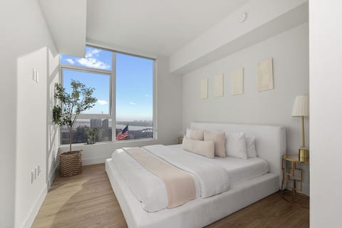 King bedroom with neutral linens, a low-profile bed and water views.