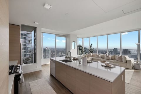 Open kitchen and living area with island seating and panoramic city views.
