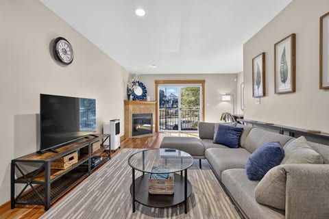 Bright living room with fireplace, large sectional, and private balcony