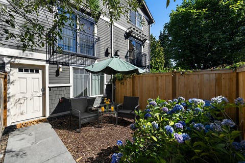 Private garden patio with lounge seating, umbrella, and blooming hydrangeas