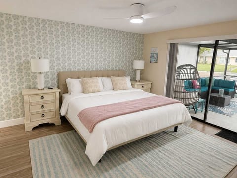 Main bedroom with hotel quality bedding, USB lamps, en-suite bathroom, smart TV, walking closets, dresser, slider to pool deck, ceiling fan and vanity/workstation