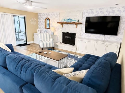 Open concept living room with large sectional sofa, smart TV, slider to pool deck and open to kitchen and dining area