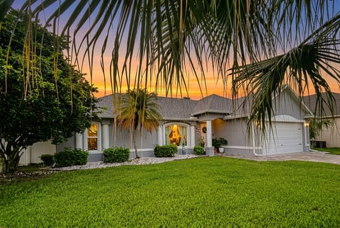 Tropical sunset curb appeal with lush lawn and inviting entry