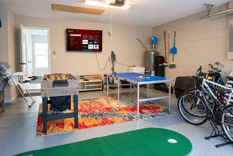Fun-filled garage game room with ping pong, foosball, TV & bikes