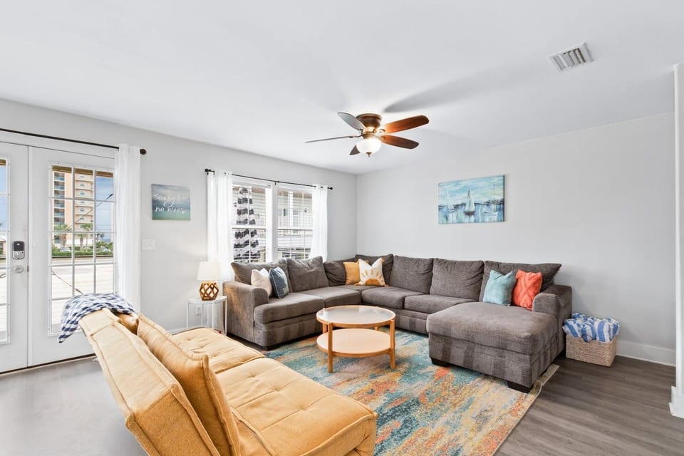Bright coastal lounge with big sectional, futon, and French doors