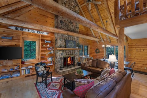 Living Room with soaring pine beams and wood burning fireplace. There is a 32" TV and books and games. We offer plenty of free wood for the fire.