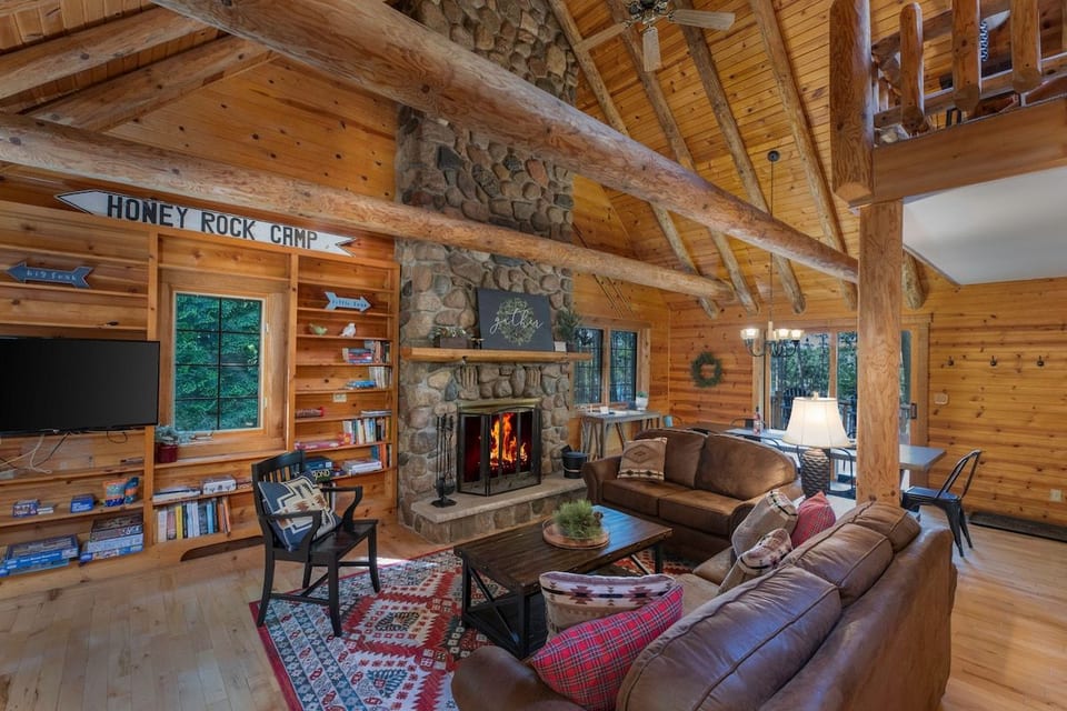 Living Room with soaring pine beams and wood burning fireplace. There is a 32" TV and books and games. We offer plenty of free wood for the fire.