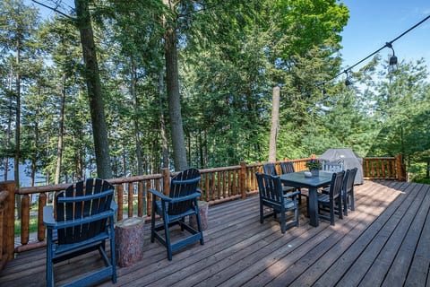 A large deck faces the lake with dining space and a Weber Gas Grill.