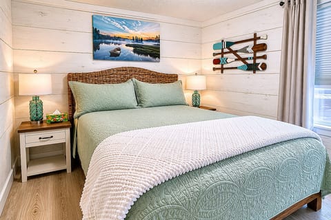 The master bedroom features a queen-size bed, complemented by generous closet storage, a full-length mirror, and bedside tables equipped with touch lamps featuring convenient charging ports, perfect for unwinding in front of the Roku TV.