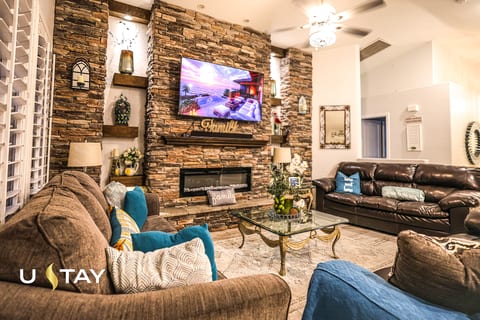 Cozy upscale living room with stone fireplace, big TV, and ample seating