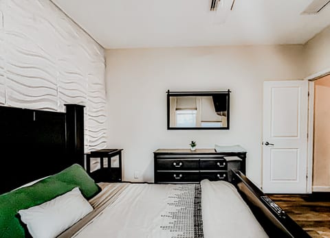 Serene modern bedroom with 3D accent wall, wood floors, storage