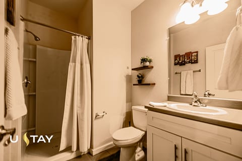 Bright full bathroom with spacious vanity, warm lighting, and tub/shower
