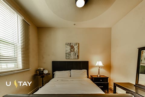 Bright, cozy bedroom with natural light, bedside tables, and dresser mirror