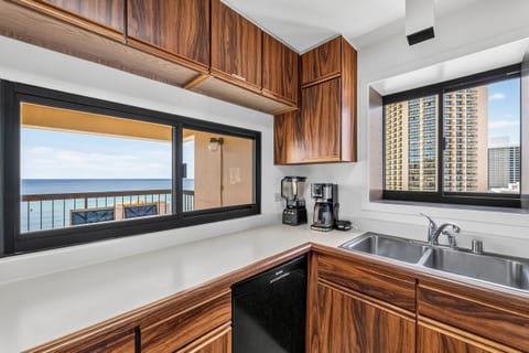 Full kitchen with an ocean view at one window, the neighboring tower at the other.