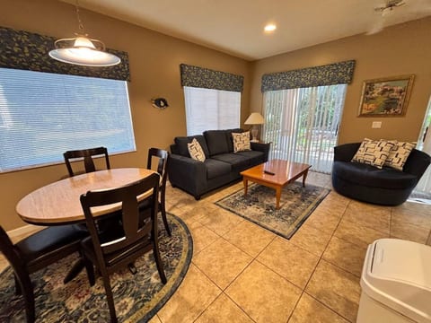Comfortable living and dining area with tile flooring, cozy seating, large windows, and an open layout.