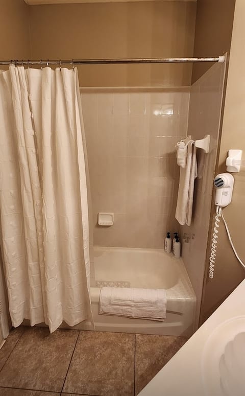 Bathroom featuring a tub/shower combination, tile surround, towel storage, and clean neutral finishes.