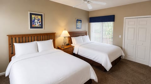 Comfortable bedroom with two beds, ceiling fan, bedside lighting, and a bright, relaxing layout.