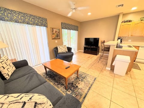 Comfortable living area with cozy seating, tile flooring, large TV, and easy access to the kitchen.