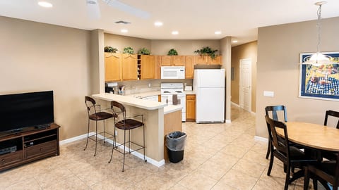 Open-concept kitchen, dining, and living area with breakfast bar seating, tile flooring, and a comfortable layout.