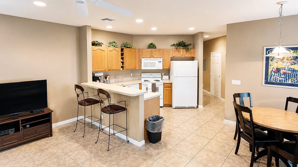 Open-concept kitchen, dining, and living area with breakfast bar seating, tile flooring, and a comfortable layout.