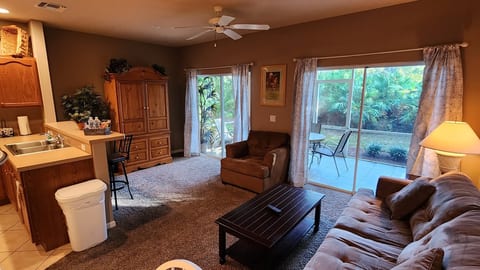 Spacious living area with comfortable furnishings, large windows, and sliding glass doors leading to the screened patio.