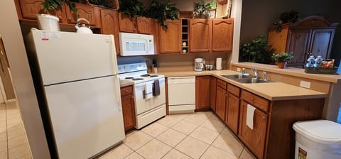 Fully equipped kitchen with full-size appliances, cabinet storage, tile flooring, and convenient counter space.
