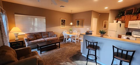 Open living and dining space with breakfast bar seating, warm lighting, and a relaxed, welcoming layout.