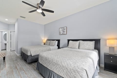 Comfortable bedroom with two beds, modern flooring, ceiling fan, and a clean, relaxing layout.