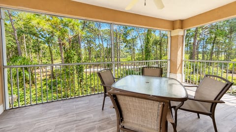 Spacious screened balcony with outdoor dining space and relaxing wooded views.