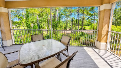 Private screened balcony with outdoor seating and peaceful views of the surrounding trees.